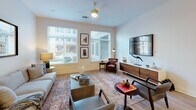This thoughtfully designed one-bedroom, one-bathroom residence delivers a clean, contemporary aesthetic across a single-level floor plan. Light-toned walls and warm wood-style flooring flow seamlessly throughout, creating a cohesive and inviting atmosphere.

The kitchen serves as a centerpiece of the open living area, featuring floor-to-ceiling white cabinetry, a full suite of stainless steel appliances including a gas range, built-in microwave, refrigerator with ice maker, and dishwasher. A large kitchen island with a bright white countertop provides ample prep space and bar-style seating, anchored by a striking linear pendant light above.

The living room is generously proportioned, bathed in natural light through multiple large windows fitted with blinds. A ceiling fan adds comfort, and the open sightlines between the living and kitchen areas enhance the sense of space.

The bedroom is a calm, well-sized retreat with neutral walls, hardwood-style floors, and direct access to a spacious walk-in closet with built-in shelving. The full bathroom features a long white vanity with an extended mirror, wood-style flooring, recessed lighting, and a shower-tub combination. Clean lines and a neutral palette give the bathroom a polished, functional feel throughout.