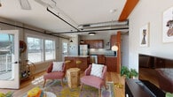 Located at 719 Lynn St in Louisville, KY, this single-floor unit blends modern industrial design with vibrant, eclectic décor. The open-concept layout seamlessly connects the living area and kitchen, creating a welcoming and functional space. Warm hardwood floors run throughout, complemented by exposed silver ductwork and bold orange accent beams that add an industrial-chic character to the interior.

The kitchen is well-appointed with warm wood cabinetry, granite countertops, a breakfast bar with seating, and a full suite of stainless steel appliances including a refrigerator, dishwasher, electric range, and microwave. Open shelving adds both practicality and style.

The living area is bright and airy, bathed in natural light from large windows, and features a ceiling fan, curated wall art, and colorful area rugs. The primary bedroom showcases a bold botanical accent wall with a rattan headboard and exposed ductwork overhead, while the second bedroom offers hardwood floors, natural light, and unique wall art. The bathroom includes a tub-shower combo with classic white subway tile and granite vanity. A stacked in-unit washer and dryer adds everyday convenience to this thoughtfully designed space.