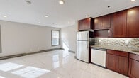 Located at 305 S Main St in Middletown, Connecticut, this two-floor space offers a thoughtfully updated interior with a clean, contemporary aesthetic. The main level features a seamlessly connected living and kitchen area, grounded by striking large-format marble-look porcelain tile flooring that reflects natural light throughout the open layout. The kitchen is well-appointed with rich dark cherry cabinetry, granite countertops, a mosaic glass tile backsplash, and a full suite of stainless steel appliances including a refrigerator, range, and dishwasher. Recessed lighting throughout the main level enhances the bright, welcoming atmosphere. A modern staircase with sleek metal balusters connects the two floors. The upper level transitions to light-toned hardwood flooring and includes multiple bedrooms, each benefiting from natural light through large windows with views of the surrounding area. Bedrooms feature closet space and baseboard heating. The bathroom is elegantly finished with floor-to-ceiling marble-patterned tile, a mosaic accent border, a soaking tub, and a rain showerhead, creating a refined, spa-like feel. Neutral wall tones and consistent trim details throughout the space lend a cohesive, move-in-ready quality to this well-maintained multi-floor unit.