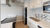 Located at 415 Washington Blvd in the vibrant Marina del Rey neighborhood of Los Angeles, this single-floor unit offers a clean, modern aesthetic with a thoughtfully designed open layout. The living area is generously proportioned, featuring light-toned luxury vinyl plank flooring that runs throughout the main living spaces, creating a seamless and cohesive feel. Large windows allow abundant natural light to pour in, casting bright, airy light across the neutral warm-gray walls and crisp white baseboards.

The kitchen is a standout feature, showcasing white shaker-style cabinetry, a decorative lattice-patterned tile backsplash, stainless steel appliances including a refrigerator, electric range, dishwasher, and microwave, as well as a stainless steel sink. A peninsula counter connects the kitchen to the living area, enhancing the open-concept flow.

The bedroom is carpeted and well-lit with natural light, offering a calm and comfortable retreat. A hallway connects the bedroom to a full bathroom, which includes a tub-shower combination with chrome fixtures and white tile surround. The entry area transitions smoothly into the main living space, completing a practical and well-organized floor plan suited for everyday living in a prime Los Angeles coastal location.