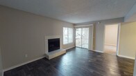 This single-floor, 2-bedroom, 2-bathroom residence offers a thoughtfully designed layout that balances open living areas with functional private spaces. The living room serves as the focal point, featuring rich dark hardwood-style flooring, a tile-surround fireplace with a raised hearth, and a sliding glass door flanked by vertical blinds that invites natural light and provides outdoor access. A large window alongside the door further brightens the space.

The kitchen is well-equipped with white shaker-style cabinetry, white quartz countertops, a gray subway tile backsplash, and stainless steel appliances including a refrigerator, electric range, and dishwasher. The open sightline between the kitchen and main living area creates a connected, functional flow throughout.

Both bathrooms are finished consistently, featuring white vanity cabinetry with quartz countertops, framed mirrors, and combination tub/shower units. Dark wood-style flooring ties each bathroom's aesthetic to the rest of the unit. Textured ceilings are present throughout, complementing the neutral wall tones that provide a clean, move-in-ready backdrop across the entire residence.