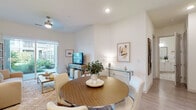 Located at 11210 Peppermint St in Louisville, Kentucky, this single-floor residence offers a thoughtfully designed open-concept layout with a clean, contemporary aesthetic throughout. The living room serves as a welcoming centerpiece, featuring light hardwood-style flooring, a ceiling fan, and expansive sliding glass doors that flood the space with natural light and open directly onto a private patio with views of a lush, landscaped courtyard. The seamless flow between the living and dining areas makes the space feel open and versatile, with neutral tones and warm lighting enhancing the inviting ambiance. The kitchen is a standout feature, boasting bold navy blue cabinetry extending to the ceiling, crisp white quartz countertops, a geometric tile backsplash, and a full suite of stainless steel appliances, including a refrigerator, range, and built-in microwave. The bedroom is a serene retreat with plush carpeting, soft neutral walls, natural light filtering through slatted blinds, and ample room for a full furniture arrangement. The bathroom is finished with large-format gray tile in a glass-enclosed walk-in shower, complemented by light tile flooring for a clean, spa-like feel. Throughout, the residence maintains a consistent palette of soft neutrals and modern finishes, creating a cohesive and comfortable living environment.