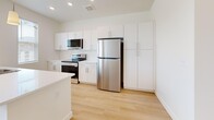 Located on S Cross Hollow Rd in Cedar City, Utah, this single-floor, one-bedroom, one-bathroom residence offers a clean, modern design throughout. Light-toned hardwood-style flooring flows through the main living areas, complementing the bright white walls and creating a fresh, airy atmosphere.

The open-concept kitchen and living area serves as the heart of the home. The kitchen is well-equipped with white shaker cabinetry, light quartz countertops, stainless steel appliances including a refrigerator, electric range, microwave, and dishwasher, as well as a deep single-basin sink. Pendant lighting and windows allowing natural light complete the polished look.

The living area features a glazed door leading to a private balcony with views of the surrounding neighborhood and terrain. The spacious bedroom is carpeted for comfort, features a ceiling fan, dual windows with outdoor views, and includes a dedicated walk-in closet. Vaulted ceilings in the bedroom area add to the sense of openness.

The full bathroom is finished with a tub-shower combination, built-in shelving, brushed nickel fixtures, and hardwood-style flooring. A dedicated laundry room houses a full-size front-loading washer and dryer with additional shelving. This well-designed residence combines functionality and modern style in a convenient Cedar City location.