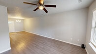 Located at 1012 Rose Garden Ln in Bentonville, Arkansas, this two-story home offers 2 bedrooms and 3 bathrooms across two well-utilized floors. The main level features a combined kitchen and living room area bathed in natural light from multiple windows. The kitchen is outfitted with crisp white cabinetry, light countertops, a central island with pendant lighting, and black appliances including a gas range, built-in microwave, dishwasher, and refrigerator. Light tile flooring completes the kitchen's clean aesthetic. The living room continues the bright, airy feel with light hardwood-style flooring, neutral tones, and a ceiling fan. A dedicated laundry room with side-by-side washer and dryer hookups adds everyday convenience. Upstairs, both bedrooms feature plush carpeting and ceiling fans. The primary bedroom is generously sized, while the secondary bedroom includes a closet and a distinctive octagonal window. Three bathrooms serve the home, each finished with white vanities and clean, simple fixtures. One bathroom features a tub-shower combo and wood-style flooring. Textured walls and popcorn ceilings are present throughout, adding character to the home's functional and straightforward design.