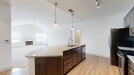 Located at 8875 Maurer Ct in Lenexa, KS, this two-story residence offers 3 bedrooms, 3 bathrooms, and a well-designed layout across two levels. The main floor centers around an open-concept kitchen and living area, where rich dark-cabinetry, a white subway tile backsplash, and stainless steel appliances — including a French door refrigerator and range — create a polished, functional space. A large granite-topped island with an undermount sink and pendant lighting serves as the focal point, flowing naturally into the living area, which features a ceiling fan and private door access. Luxury vinyl plank flooring runs throughout the main level, adding warmth and durability. The upper floor houses all three bedrooms, each finished with plush neutral carpet and ceiling fans. The generously sized primary bedroom includes a walk-in closet with built-in shelving and a dedicated en-suite bathroom featuring a glass-enclosed shower, dark wood vanity, and light quartz countertops. A second full bathroom with a tub-shower combination and matching dark cabinetry serves the additional bedrooms. Two closets and dual staircase access round out a practical and comfortable floor plan.