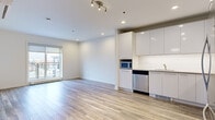Located at 8035 Boul du St-Laurent in Brossard, Quebec, this well-appointed one-bedroom, one-bathroom unit offers a thoughtfully designed open-concept layout with modern finishes throughout. Light-toned hardwood-style flooring runs continuously across the living, dining, and kitchen areas, creating a cohesive and airy feel. The kitchen is a standout feature, showcasing high-gloss white cabinetry extending to the ceiling, white subway tile backsplash, light countertops, and a full suite of stainless steel appliances including a refrigerator, electric range, built-in microwave, and dishwasher. The open living area is bright and welcoming, benefiting from natural light through large windows and sliding glass door access to a private balcony with outdoor views. The bedroom is a comfortable size, featuring hardwood-style flooring, a large window framing exterior views, and a sleek glass-paneled sliding door. The bathroom is finished with modern wood-accented vanity cabinetry, a wide white countertop, a large mirror, and in-unit stacked washer and dryer for added convenience. Recessed lighting and track lighting fixtures throughout complete the clean, contemporary aesthetic of this well-designed Brossard residence.
