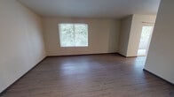 Located in Tacoma, WA, this single-floor unit at 1007 115th Street Ct E offers a clean, modern living environment with thoughtfully selected finishes throughout. The open living area features smooth hardwood-style flooring and neutral-toned walls, creating a bright and welcoming atmosphere. Large windows dressed with blinds allow ample natural light to flow in while offering views of the surrounding greenery.

The kitchen is well-equipped with white shaker-style cabinetry, light granite-look countertops, stainless steel appliances including a refrigerator and electric range, and a peninsula that provides additional workspace and casual seating potential. A ceiling fan adds comfort and airflow to the kitchen area.

The bedrooms are carpeted for warmth and comfort, each featuring windows that bring in natural light and baseboard heating for year-round climate control. Dark-toned interior doors add a contemporary contrast to the neutral walls.

Both bathrooms are finished with white vanity cabinetry, granite-style countertops, large mirrors with modern light fixtures, and tub-shower combinations featuring marbled tile surrounds and hardwood-style flooring. The entry area provides a practical transition space into the unit. Overall, the space presents a clean, functional, and modern aesthetic suited for comfortable everyday living.