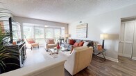 This single-floor residence offers a thoughtfully designed layout that balances open communal spaces with comfortable private quarters. The living room serves as the heart of the home, featuring rich wood-look flooring, a textured ceiling, and large windows that invite an abundance of natural light and views of the surrounding greenery. The space flows seamlessly into a defined dining area, which is anchored by a dark-toned dining table and accented by neutral walls that create a clean, contemporary feel.

The kitchen makes a bold statement with dark cabinetry, glossy black subway tile backsplash, granite-style countertops, and stainless steel appliances, striking a sleek contrast against the lighter tones found elsewhere in the residence. A breakfast bar connects the kitchen to the dining space, enhancing the open-concept flow.

Both bedrooms offer a tranquil retreat, with plush carpeting, neutral walls, and ample room for furnishings. Each bedroom is accompanied by its own full bathroom, both finished with dark vanity cabinetry, granite countertops, wood-look flooring, and a tub-shower combination. The overall design throughout the residence is cohesive, blending modern finishes with warm, inviting tones to create a comfortable and functional living environment.