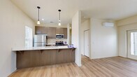 Located in Vancouver, WA, this well-appointed 2-bedroom, 4-bathroom residence offers a thoughtfully designed single-level layout. The open-concept living and kitchen area serves as the heart of the home, featuring light wood-style plank flooring that extends throughout the main living spaces. The kitchen is outfitted with warm taupe cabinetry, stainless steel appliances including a refrigerator, range, and microwave, and a sleek quartz peninsula countertop with an undermount sink and pendant lighting above — ideal for both cooking and casual dining. The living area is bright and airy, with natural light flowing in through large windows and a glass door that opens to a private balcony. The two bedrooms are carpeted for comfort, with the primary bedroom offering a generous walk-in closet equipped with wire shelving systems. The four bathrooms are finished with wood-toned vanities, white quartz countertops, and brushed nickel fixtures, with at least one full bath featuring a soaking tub and shower combination. Neutral cream-toned walls throughout create a clean, cohesive aesthetic that complements the modern finishes. This residence combines functional design with contemporary style in a compact yet efficient floor plan.