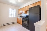 Located at 1478 Parkside Ave in Ewing, NJ, this single-floor unit offers a straightforward, functional layout with a clean and bright aesthetic throughout. Polished hardwood flooring extends across the main living areas, adding warmth and a sense of continuity to the space. The open living area is generously proportioned, featuring crisp white walls, baseboard heating, and natural light that enhances the airy feel of the room. A hallway connects the living space to the remaining rooms, maintaining an organized flow throughout the unit.

The kitchen is thoughtfully equipped with warm wood cabinetry offering ample upper and lower storage, dark speckled countertops, a stainless steel sink, and black appliances including a gas range and refrigerator. The layout provides efficient use of space for everyday cooking needs.

The bedroom continues the hardwood flooring found throughout the unit and includes a closet and a window that allows natural light to filter in, creating a comfortable and functional room.

The bathroom features tile flooring, a wood-toned vanity, and a full tub and shower combination enclosed by sliding frosted glass doors with chrome hardware. A window above the tub provides ventilation and additional light. Baseboard heating is present, ensuring comfort throughout the unit.