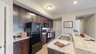 Located at 3820 Codet Rd in Columbus, OH, this single-floor residence offers a well-designed layout with a cohesive, neutral color palette throughout. The kitchen serves as a functional centerpiece, featuring rich dark-brown cabinetry extending to the ceiling for ample storage, light granite countertops, black appliances including a refrigerator, range, and built-in microwave, and a breakfast bar with seating that opens toward the living area. Wood-look flooring runs through the kitchen and main living spaces, lending warmth and continuity.

The living room is generously proportioned, with neutral walls, carpet flooring, and French doors that open to a private balcony, allowing natural light to fill the space. The bedrooms are comfortably sized and carpeted, each offering a calm, restful atmosphere with neutral tones and good closet access. The bathroom features tile flooring, a dark-cabineted vanity with a granite-style countertop, and clean, straightforward finishes.

A dedicated laundry area with a full-size Whirlpool washer and dryer adds everyday convenience. Overall, the space presents a practical and comfortable layout with consistent finishes throughout.