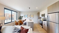 Located at 1002 South Racine Avenue in Chicago's dynamic West Loop, this thoughtfully designed 3-bedroom, 2-bathroom residence offers a modern open-concept floor plan across a single level. Light wood flooring flows throughout, unifying the living, dining, and kitchen areas into a cohesive, airy space. The contemporary kitchen is a standout feature, equipped with stainless steel appliances, a two-tone cabinetry scheme combining white gloss and warm wood-toned cabinets, and a large center island with a white quartz countertop that accommodates bar seating — ideal for casual dining or entertaining. The open layout connects seamlessly to a dedicated dining area bathed in natural light from oversized windows. The primary bedroom is a comfortable retreat with warm neutral tones and direct access to a private bathroom featuring a modern wood-grain vanity, clean-lined mirror, and light tile flooring. Additional bedrooms offer generous natural light, with one room showcasing dual large windows framing neighborhood views. Both bathrooms echo a consistent modern aesthetic with understated finishes. A dedicated closet and well-proportioned hallways round out the functional layout, while the neutral palette and clean architectural lines lend the entire space a calm, contemporary ambiance.