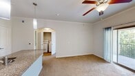 This 570 square foot apartment in Austin, TX offers a thoughtful layout maximizing space efficiency. The modern kitchen is a standout feature, boasting rich wood cabinetry, stainless steel appliances, and granite countertops. A blue glass tile backsplash adds a pop of color, while pendant lighting illuminates the kitchen island. The living area flows seamlessly from the kitchen, featuring wood-style flooring and plush carpeting in the bedroom. Large windows in the bedroom allow ample natural light, complemented by a ceiling fan for comfort. The bathroom continues the modern aesthetic with a granite vanity top and wood cabinetry. Throughout the apartment, neutral wall colors create a blank canvas for personalization. The efficient design includes a hallway and closet space, ensuring storage needs are met in this compact yet functional living space.