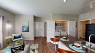 This single-story residence in Humble, Texas offers a well-organized, open-concept floor plan accommodating two bedrooms and two full bathrooms. Wood-style flooring runs throughout the main living areas, lending warmth and visual continuity across the space.

The living room serves as a central gathering area, featuring multiple windows that admit natural light and vaulted-style wall angles that add subtle architectural interest. A dedicated dining area sits adjacent to the living space, creating a seamless flow for everyday living and entertaining.

The kitchen is efficiently laid out with light wood cabinetry, dark countertops, and black appliances including a refrigerator, range, and built-in microwave. A breakfast bar with seating connects the kitchen to the main living area, adding both function and an informal dining option.

Both bedrooms are comfortably sized and feature ceiling fans and walk-in closets, offering practical storage solutions. Each full bathroom includes a tub-shower combination with tile surround and wood-style flooring. A hallway connects the secondary bathroom to the adjacent bedroom for convenient access.

A notable feature is the in-unit laundry closet, which houses a full-size washer and dryer. Neutral wall tones throughout create a versatile backdrop adaptable to a range of interior styles.