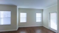 Located in Denton, TX, this single-story space offers a straightforward and functional layout with a clean, understated aesthetic. The interior is finished with neutral, light beige walls that create a bright and open atmosphere, complemented by crisp white crown molding and baseboards that add a polished architectural detail throughout. The flooring consists of rich, dark wood-style planks that provide a warm contrast to the lighter walls and ceiling, lending a sense of depth and continuity to the space. Two windows dressed with white horizontal blinds allow natural light to filter into the room, keeping the environment well-lit while offering privacy and light control. The smooth white ceiling enhances the sense of openness and contributes to the overall airy feel of the interior. The room's clean lines and minimal detailing give the space a versatile, move-in-ready quality suitable for a variety of uses and furnishing styles. The combination of durable flooring, neutral tones, and natural light makes this Denton property a practical and welcoming option.