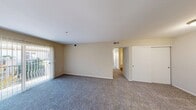 Located at 31990 Castaic Rd in Castaic, California, this single-story, 2-bedroom, 1-bathroom unit offers a practical and comfortable layout across a well-utilized floor plan. The living area is carpeted and features warm neutral-toned walls, a sliding glass door fitted with vertical blinds that allows natural light to filter in and provides access to an outdoor area. A dedicated entry door opens into the living space, with a kitchen positioned adjacent, equipped with wood-toned cabinetry and white appliances including a refrigerator and range. A hallway connects the main living area to the private quarters, leading to two carpeted bedrooms, each featuring windows with blinds that bring in natural light. The primary bedroom is generously proportioned and includes its own closet space. In total, the unit features four closets, providing notable storage throughout. The full bathroom includes wood-toned cabinetry with a vanity sink, a large mirror, and wood-look flooring, offering a clean and functional design. The overall color palette of beige and white tones creates a neutral, move-in-ready ambiance throughout the unit.