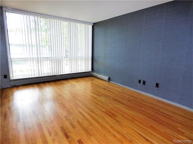 Sala de estar con ventanas del tamaño de una pared y piso de madera. - 125 E 14 Mile Rd