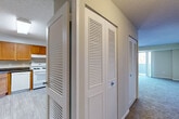 This two-bedroom, one-bathroom residence at 14000 Castle Blvd in Silver Spring, Maryland offers a practical and comfortable single-floor layout. The living room is generously proportioned, featuring plush wall-to-wall carpeting, neutral toned walls, and a textured ceiling. A full-width sliding glass door opens to a private balcony overlooking a natural wooded setting, allowing ample natural light to fill the space. The kitchen is outfitted with warm honey-toned wood cabinetry, dark laminate countertops, a tile-effect vinyl floor, and white appliances including a gas range and refrigerator. A skylight adds brightness to the cooking area. The hallways are well-organized and lined with louvered bi-fold closet doors, providing excellent storage throughout. The primary bedroom is a comfortable size and includes its own closet access. The full bathroom features a tub-shower combination with white tile surround, a white vanity, and wood-look flooring with clean, bright finishes. Two hallways connect the rooms efficiently, contributing to a logical and functional flow. The textured ceilings are consistent throughout, giving the home a cohesive aesthetic. Overall, this residence offers a balanced combination of storage, natural light, and outdoor connectivity in a quiet Silver Spring location.