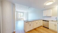 Located at 170 Washington Street in Haverhill, MA, this studio offers a well-organized, single-floor layout that makes efficient use of its space. The open-concept design seamlessly connects the kitchen and living area, creating a bright and functional environment throughout.

The kitchen is a standout feature, equipped with crisp white shaker cabinetry, a classic white subway tile backsplash, and a full suite of stainless steel appliances including a refrigerator, range, microwave, and dishwasher. A peninsula with a neutral-toned countertop provides additional prep space and serves as a natural divider between the kitchen and living area.

The living area is bathed in natural light from a large window with street views, complemented by light hardwood-style flooring that runs throughout the unit. Neutral gray wall tones and clean white trim contribute to a calm, contemporary aesthetic. Track lighting adds a modern touch to the open living space.

The bathroom is neatly appointed with a white vanity, quartz-style countertop, chrome fixtures, a combination tub and shower, and a well-lit mirror. Two closets provide practical storage, while a hallway connects the key spaces of the unit efficiently. Overall, the studio presents a clean, modern, and move-in-ready environment.
