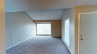 This single-floor residence offers a thoughtfully laid-out interior with a warm, neutral color palette carried consistently throughout every room. The standout feature is the living room, which boasts a dramatic vaulted ceiling that creates a sense of openness and volume well above what the footprint alone would suggest. Two large windows fitted with horizontal blinds flood the space with abundant natural light, enhancing the airy feel. Plush wall-to-wall carpeting extends through the living area and into the bedrooms, adding comfort underfoot.

The dining area flows naturally from the living space, marked by a pendant light fixture overhead and open sightlines into the kitchen. The kitchen is efficiently designed with white cabinetry, granite-look laminate countertops, a double stainless steel sink, a white electric range, and a dishwasher, all set over wood-look flooring.

The bathroom features a tub-shower combo with tile surround, a toilet, and a vanity with a granite-look countertop, white cabinetry, and a large mirror illuminated by a multi-bulb light bar.

The bedrooms are generously sized, carpeted, and finished with textured ceilings. One bedroom includes a window with natural light, while both offer clean, neutral walls ready for personalization. The overall ambiance is clean, functional, and move-in ready.