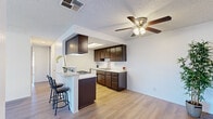 Located in Palmdale, CA, this single-floor, 2-bedroom, 2-bathroom residence offers a well-organized and efficiently designed living space. The open-concept layout connects the living room and kitchen, creating a cohesive and practical flow throughout the home. Light wood-style flooring runs throughout, complemented by crisp white walls and textured ceilings that lend a clean, uniform aesthetic.

The kitchen is a standout feature, outfitted with rich dark-brown cabinetry extending from floor to ceiling, granite-style countertops, a gas range with hood, dishwasher, and a double sink. A peninsula with a breakfast bar provides additional seating and workspace, making the kitchen both functional and social. A skylight and ceiling fan with integrated lighting enhance brightness and comfort in this central area.

The spacious primary bedroom offers a dedicated closet and a window dressed with vertical blinds for adjustable natural light. The second bedroom is comparably well-sized with its own closet access. Both bathrooms are finished with matching granite-style countertops, dark cabinetry, large mirrors, and shower-tub combinations. Each room reflects a consistent, clean design language throughout the home, making it a practical and comfortable residence.