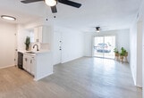 Located at 1601 N Lee Trevino Dr in El Paso, Texas, this single-floor unit offers a clean, bright, and functional layout designed for comfortable living. The open-concept living area greets you at the entrance, showcasing light-toned vinyl plank flooring, crisp white walls, and a ceiling fan with light fixture. A large sliding glass door floods the space with natural light and provides views of the surrounding exterior. The living area flows seamlessly into the kitchen, which features white shaker-style cabinetry, subway tile backsplash, a breakfast bar peninsula, and black appliances including a gas range and refrigerator. The bedrooms are carpeted for added comfort, each equipped with ceiling fans and windows that allow in natural light. The primary bathroom offers a dual-sink vanity with modern matte black fixtures, mirrors, and a separate tub and shower area. A second full bathroom continues the clean aesthetic with white tile surround, wood-look flooring, and matte black hardware accents. Throughout the unit, the consistent white color palette and updated finishes create a cohesive, move-in-ready atmosphere suited for a variety of lifestyles.