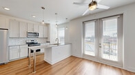 Located at 5141 Stone Mountain Hwy in Stone Mountain, GA, this well-designed one-bedroom, one-bathroom unit offers a clean, modern aesthetic throughout its efficiently laid-out single floor. The open-concept living and kitchen area serves as the heart of the home, showcasing hardwood-style flooring, white shaker cabinetry, subway tile backsplash, and a granite-topped kitchen island with pendant lighting overhead. Stainless steel appliances, including a range, microwave, and refrigerator, complete the kitchen. A ceiling fan and French doors lead to a private balcony, filling the living space with natural light. The bedroom features plush carpeting, a ceiling fan, and a distinctive sliding barn door that connects to the rest of the unit. A dedicated closet provides convenient storage. The hallway, finished with recessed lighting and clean white walls, connects all areas seamlessly. The bathroom is well-appointed with a tub-shower combo, subway tile surround, wood-look flooring, and a granite vanity with brushed nickel fixtures. Throughout the unit, crisp white walls and consistent finishes create a bright, cohesive, and move-in-ready living environment.