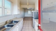 Located at 1132 Phoenix Ave in Seaside, California, this single-story, one-bedroom, one-bathroom home offers a thoughtfully efficient layout. A defining architectural feature throughout the home is the white-painted wood plank ceiling with exposed beams, lending a clean, cottage-like character to the interior.

The living room is carpeted and open, connecting seamlessly to the galley-style kitchen. The kitchen is outfitted with white cabinetry, light countertops, tile flooring, a stainless steel refrigerator, and a gas range, with a rear door providing direct access to the balcony and allowing natural light to filter in.

The bedroom is a comfortable, carpeted space with its own window overlooking the exterior, allowing in natural light. Two closets provide ample storage within the home. A hallway connects the main living areas to the bedroom and bathroom.

The full bathroom features tile flooring, a tub-shower combination with a sliding glass enclosure, a vanity with a white countertop, and a frosted window above the shower for added privacy and light.

Completing the home is a private balcony, accessible from the kitchen, ideal for enjoying Seaside's mild coastal climate. The overall ambiance is bright, clean, and functional—a well-organized home suited for comfortable everyday living.