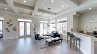 Located at 4531 Langdon Rd in Morrisville, NC, this sophisticated single-floor space offers a seamlessly designed interior that balances modern aesthetics with functional comfort. The main living area immediately impresses with its distinctive coffered ceiling detail, recessed lighting, and smooth light-toned hardwood flooring that runs throughout the space, lending a clean and cohesive feel.

Large double-pane windows line the walls, flooding the interior with abundant natural light and offering views of the surrounding exterior. Glass-paneled entry doors further enhance the openness, creating a welcoming and airy atmosphere from the moment you step inside.

The lounge area is thoughtfully appointed, featuring a contemporary seating arrangement with dark leather accent chairs, a sleek sofa, and a cowhide-upholstered bench that adds a stylish contrast to the neutral palette. A bar-height counter with seating along one wall provides an additional gathering spot, ideal for casual conversation or refreshments.

The overall ambiance is polished and refined, with a neutral color scheme of soft whites and warm grays that creates a calm, professional environment. Carefully selected furnishings and layered area rugs define each zone within the open layout, contributing to a space that is both inviting and elegantly functional.