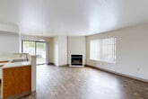 Located at Constitution Square Heights in Colorado Springs, CO, this single-floor, 2-bedroom, 2-bathroom residence offers a functional and well-organized layout. The open-concept living and dining area is a highlight of the home, featuring wood-style plank flooring, neutral tones, and a fireplace as a central focal point. Large windows with vertical blinds fill the space with natural light, while a sliding glass door provides access to one of two private patios, extending the living area outdoors. The kitchen is equipped with white appliances including an electric range, built-in microwave, and dishwasher, complemented by warm wood-trimmed cabinetry, light countertops, a double sink, and a pendant light overhead. Both bedrooms are carpeted and receive natural light, with the spacious primary bedroom offering a generously sized walk-in closet with wire shelving. A second well-proportioned bedroom also includes dedicated closet space. The two bathrooms feature wood-style flooring, wood-trimmed vanities, and a tub-shower combination. Additional conveniences include an in-unit laundry area and four total closets throughout, providing ample storage. The overall ambiance is clean, bright, and move-in ready.