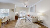 Located at 1900 Walnut St in Bastrop, Texas, this thoughtfully designed 2-bedroom, 2-bathroom residence offers a comfortable and stylish single-floor layout. The open-concept living and dining area serves as the heart of the home, featuring warm hardwood-style flooring, crown molding, and a ceiling fan that enhances air circulation throughout. Natural light pours in through multiple windows and a set of French doors, creating a bright and welcoming ambiance. The kitchen is well-equipped with rich cherry-toned cabinetry, granite-style countertops, white appliances, a tile backsplash, and a breakfast bar that connects seamlessly to the living space. The spacious primary bedroom includes a ceiling fan, large windows with outdoor views, and access to a generous walk-in closet fitted with wire shelving and ample storage. Both bathrooms are clean and functional, with one featuring a soaking tub, wide vanity with white cabinetry, and hardwood-style flooring. The second bedroom is bright and comfortably sized. A connecting hallway links all rooms efficiently. Throughout the residence, neutral tones and consistent flooring create a cohesive, inviting atmosphere well-suited for everyday living.