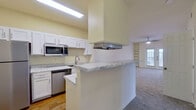 This single-story, 2-bedroom, 2-bathroom residence offers a thoughtfully designed layout across a comfortable footprint. The kitchen is a functional highlight, featuring white shaker-style cabinetry, marble-patterned countertops, stainless steel appliances including a refrigerator, microwave, and dishwasher, and durable hardwood-style flooring. A peninsula with additional counter space connects the kitchen to the living area, creating an open and accessible flow. The living room is bright and inviting, with vaulted ceilings, a ceiling fan, soft carpeting, built-in shelving, and French doors that allow natural light to fill the space. The primary bedroom offers a generous layout, carpeted floors, a ceiling fan, and large windows with exterior views. A dedicated walk-in closet with wire shelving provides ample storage. Both bathrooms are finished consistently, featuring white vanities with marble-style countertops, hardwood-style flooring, and tiled tub-shower combinations with decorative accent tile. The space maintains a clean, neutral palette throughout, contributing to a bright and cohesive ambiance.