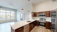 Located at 1107 S 44th St in Cumming, Iowa, this well-appointed 2-bedroom, 2-bathroom single-floor residence offers a thoughtfully designed layout with modern finishes throughout. The open-concept kitchen serves as the heart of the home, showcasing rich dark walnut cabinetry, crisp white countertops, and a full suite of stainless steel appliances including a range, microwave, dishwasher, and refrigerator. A large kitchen island with an undermount sink provides additional workspace and a natural gathering point. Dramatic soaring ceilings and gold-toned pendant lighting lend the living and kitchen area a bright, airy ambiance, complemented by light wood-look flooring that flows seamlessly throughout. The primary bedroom is generously proportioned, featuring high ceilings and ample closet space. The second bedroom benefits from a tall window that invites natural light and outdoor views. Both bathrooms are clean and functional, with one featuring a full tub-shower combination. A dedicated in-unit laundry room with side-by-side washer and dryer adds everyday convenience. Five closets provide exceptional storage throughout the home, rounding out this efficiently planned and stylishly finished residence.