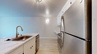 This one-bedroom, one-bathroom unit in Lafayette, CA offers a thoughtfully arranged single-level layout that maximizes its compact footprint. The combined kitchen and living area forms the heart of the space, finished with light wood-tone flooring that lends a clean, contemporary feel throughout. The kitchen is equipped with stainless steel appliances—including a refrigerator, range, and dishwasher—complemented by white cabinetry and marble-look countertops that extend to a functional sink area. A geometric ceiling light fixture adds a modern accent overhead.

The living area benefits from a full-height sliding glass door that opens to a balcony overlooking lush greenery and a pool, filling the room with natural light and providing pleasant outdoor views. The bedroom, carpeted for comfort, features its own window with similar pool and tree views, creating a serene atmosphere. A dedicated walk-in closet with built-in shelving and hanging rods provides organized storage.

The bathroom is finished in a neutral palette with tile flooring, a white vanity topped with a marble-look surface, a framed mirror, contemporary black hardware accents, and a tub-shower combination. Throughout the unit, warm beige tones and clean white trim create a cohesive, move-in-ready aesthetic.