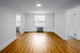 Unit 309 at 262 Jarvis Street in Toronto presents a thoughtfully arranged single-floor layout comprising a living room, kitchen, two bathrooms, and an entrance. Throughout the unit, light-toned laminate wood flooring creates a warm, cohesive aesthetic that flows from room to room.

The living room is an open, bright space featuring large windows that admit natural light and offer views of the surrounding neighbourhood. Classic cast-iron radiators line the walls beneath the windows, nodding to the building's heritage character. Crown moulding adds a refined architectural detail to the otherwise clean, white-painted walls and ceilings.

The kitchen is efficiently designed with white cabinetry, a tiled backsplash, and light tile flooring that distinguishes it from the rest of the unit. Stainless steel appliances, including a refrigerator and stove, are included. A recessed ceiling light and window provide both illumination and ventilation.

The entrance hallway connects the rooms cleanly, with additional corridors providing access to both bathrooms. One bathroom features white subway-tiled walls surrounding a full bathtub, a toilet, a radiator, and a window, maintaining the unit's consistent clean and minimal aesthetic throughout.
