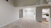 Located at 7843 Roswell Rd in Sandy Springs, GA, this multi-level 2-bedroom, 2-bathroom home is thoughtfully arranged across three floors. The main living level serves as the heart of the home, offering a generous open-plan living and dining area with soaring vaulted ceilings, plush neutral carpeting, and a ceiling fan that enhances airflow and comfort. A striking fireplace with a dark tile surround anchors the living space, while sliding glass doors lead to an outdoor balcony, inviting natural light and views of the surrounding greenery. An elegant chandelier illuminates the adjacent dining area, which connects seamlessly to the kitchen pass-through. The upper level features a spacious loft-style area with angled ceilings, a ceiling fan, and a window framing outdoor views — ideal for a secondary lounge or home office. Both bedrooms are carpeted and well-proportioned, with the generously sized primary bedroom offering ample room to accommodate a full suite. Each of the two bathrooms is clean and functional, featuring full tub-shower combinations with white tile surrounds and mirrored vanities. Two closets and a hallway provide practical storage throughout. The lower entry level completes the layout, with staircases connecting all three floors efficiently.