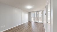 Located at 140 Main St W in the heart of Hamilton, Ontario, this well-designed one-bedroom, one-bathroom unit offers a thoughtfully efficient layout with modern finishes throughout. Warm wood-look laminate flooring flows seamlessly across every room, complementing the crisp white walls and clean contemporary aesthetic.

The living room is a bright, open space anchored by large sliding glass doors that lead to a private balcony, offering views of Hamilton's urban skyline. The balcony provides an ideal outdoor retreat with an elevated city perspective.

The kitchen features flat-front white cabinetry extending to the ceiling for generous storage, paired with stainless steel appliances including a refrigerator, electric range, and built-in microwave. Light countertops and matching flooring give the kitchen a cohesive, modern feel.

The bedroom is a comfortable, well-proportioned room filled with natural light from a large window. It includes a sliding-door closet, providing practical built-in storage. The four-piece bathroom is finished with crisp white subway tile surrounding a soaker tub and shower combination, complemented by clean white fixtures throughout.

A welcoming hallway entry connects all areas of the unit, giving the layout a logical and functional flow. The overall ambiance is bright, clean, and move-in ready.