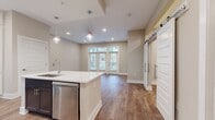 This 670 square foot single-floor living space offers a modern and efficient layout. The heart of the home is an open-concept area that combines the kitchen and living room, promoting a sense of spaciousness and connectivity. Large windows, including a set of three with transom lights, flood the space with natural light and provide views to the outside, enhancing the room's airy feel.

The flooring throughout is a durable and attractive wood-look material, likely luxury vinyl plank, which adds warmth and character to the space. The walls are painted in a neutral tone, creating a blank canvas for personalization. Recessed lighting in the ceiling ensures even illumination throughout the day and night.

The living area is generously sized, allowing for flexible furniture arrangements. The kitchen, while not visible in the image, is integrated into this open space, likely featuring modern appliances and ample storage to maximize the compact footprint.

A single bathroom and closet complete the floorplan, providing essential amenities within the efficient layout. This space is ideal for those seeking a low-maintenance lifestyle without sacrificing comfort or style. Its design makes excellent use of the available square footage, creating a home that feels larger than its actual dimensions suggest.