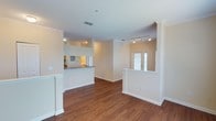 This single-floor residence offers a thoughtfully designed open-concept layout that promotes a seamless flow between living spaces. Rich hardwood flooring extends throughout the main living area, adding warmth and character to the interior. The space is bathed in a neutral, light beige color palette that enhances the sense of openness and creates a welcoming ambiance.

The kitchen is semi-open to the main living area, separated by a half-wall breakfast bar with granite countertops — a functional and stylish design choice that maintains visual connectivity between spaces. Warm cabinet finishes and under-cabinet lighting give the kitchen an inviting glow.

Track lighting installed in the living area provides flexible, directed illumination, complementing the natural light that pours in through elegant French doors visible at the rear of the space. These glass-paneled doors serve as both a design focal point and a source of abundant natural brightness.

Architectural details including crown molding, clean white baseboards, and a textured ceiling add subtle refinement throughout. HVAC vents are thoughtfully placed to ensure consistent comfort. The layout is further defined by partial walls that create distinct zones while preserving the open, airy feel that defines this well-appointed single-floor space.