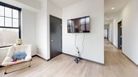 Located at 2127 Marshall Ave in Saint Paul, Minnesota, this well-appointed one-bedroom, two-bathroom unit offers a thoughtfully designed layout across a single floor. The open-concept kitchen and living area serves as the heart of the space, featuring light wood-tone flooring, recessed lighting, and an abundance of natural light streaming through large, black-framed windows. The kitchen is outfitted with stainless steel appliances, warm wood-grain cabinetry, a white subway tile backsplash, and a generous island with bar seating — ideal for both cooking and casual dining. The living area flows seamlessly from the kitchen, offering views of the surrounding neighborhood through expansive windows. A hallway connects the main living space to the private bedroom, which features carpeted flooring, large windows, and ample closet storage — with six closets total throughout the unit providing exceptional organization. The primary bathroom includes dual sinks, gray cabinetry, and a wide vanity mirror, while also incorporating in-unit laundry. A second full bathroom features light wood flooring and a tub/shower combination. Dark-trimmed doors and a consistent modern aesthetic tie the entire space together with a clean, contemporary feel.