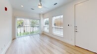 Located at 2217 N Fitzhugh Ave in Dallas, TX 75204, this modern single-floor unit offers a thoughtfully designed layout making excellent use of its compact footprint. Light hardwood flooring flows throughout the main living spaces, lending warmth and continuity to the interior.

The combined kitchen and living area is a standout feature, with the kitchen showcasing sleek white cabinetry, dark countertops, a white hexagonal tile backsplash, stainless steel appliances including a refrigerator, range, microwave, and a wine cooler. The living area benefits from an abundance of natural light pouring through a sliding glass door and adjacent windows, offering views of outdoor greenery. A ceiling fan completes the airy, comfortable atmosphere.

Two well-appointed bathrooms provide functional elegance. The primary bathroom features a floating white vanity with a dark countertop, an illuminated frameless mirror set against a warm wood-slat accent wall, and cool gray tile flooring. The secondary bathroom offers a frameless glass-enclosed shower and matching gray tile floors, maintaining the clean, minimalist aesthetic.

A dedicated laundry area houses a stacked Samsung washer and dryer, adding everyday convenience. The overall design is clean, modern, and cohesive, making this Dallas property a refined and efficient urban living space.