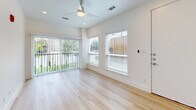 Located at 2217 N Fitzhugh Ave in Dallas, TX 75204, this modern single-floor unit offers a thoughtfully designed layout making excellent use of its compact footprint. Light hardwood flooring flows throughout the main living spaces, lending warmth and continuity to the interior.

The combined kitchen and living area is a standout feature, with the kitchen showcasing sleek white cabinetry, dark countertops, a white hexagonal tile backsplash, stainless steel appliances including a refrigerator, range, microwave, and a wine cooler. The living area benefits from an abundance of natural light pouring through a sliding glass door and adjacent windows, offering views of outdoor greenery. A ceiling fan completes the airy, comfortable atmosphere.

Two well-appointed bathrooms provide functional elegance. The primary bathroom features a floating white vanity with a dark countertop, an illuminated frameless mirror set against a warm wood-slat accent wall, and cool gray tile flooring. The secondary bathroom offers a frameless glass-enclosed shower and matching gray tile floors, maintaining the clean, minimalist aesthetic.

A dedicated laundry area houses a stacked Samsung washer and dryer, adding everyday convenience. The overall design is clean, modern, and cohesive, making this Dallas property a refined and efficient urban living space.