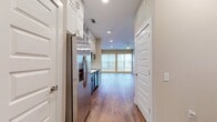 This 560 square foot apartment maximizes functionality in a compact layout. The open-concept design combines the kitchen and living room, creating a spacious feel despite the modest dimensions. The room features warm, neutral-toned walls that complement the rich, wood-like flooring, enhancing the overall aesthetic.

Recessed lighting and a modern ceiling fan with an integrated light fixture provide ample illumination, while large windows allow natural light to flood the space. The windows, adorned with horizontal blinds, offer privacy and light control.

The apartment boasts clean lines and a contemporary aesthetic, with baseboards and crown molding adding a touch of sophistication. A visible doorway suggests access to additional areas, likely leading to the bathroom or closet mentioned in the property summary.

The efficient design appears to make the most of the available square footage, ideal for those seeking a cozy yet stylish living space. The neutral color palette and modern fixtures create a blank canvas, allowing for personalization to suit various tastes and lifestyles.