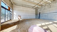 Located at 850 S Gadsden St in downtown Tallahassee, FL, this single-floor commercial shell space presents a blank canvas ready for tenant build-out. The structure is built with concrete masonry unit (CMU) walls, exposed concrete columns, and a robust concrete block construction that conveys durability and an industrial character throughout.

The space is configured as one open, column-punctuated floor, offering generous square footage ideal for retail, office, or mixed-use purposes. The front facade features large, floor-to-ceiling storefront windows with sleek black metal framing, flooding the interior with abundant natural light and providing clear sightlines to the surrounding streetscape. A glass entry door provides direct access from the street.

The rear and side portions of the space showcase exposed CMU walls alongside roughed-in overhead plumbing and conduit runs, indicating that mechanical and utility infrastructure is already in progress. The earthen subfloor is currently unprepared, signaling early-stage construction, while pink insulation materials and construction debris reflect active development work.

The ceiling height is notably generous, enhancing the sense of volume and offering flexibility for future interior configurations. With its prominent street-facing glazing, sturdy masonry shell, and central Tallahassee location, this space holds strong potential for a wide variety of commercial uses.