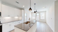 This modern single-story home in Denton, TX offers a thoughtfully designed layout with three bedrooms, two bathrooms, and three closets. The open-concept kitchen and living area serves as the heart of the home, featuring a large granite-topped island with an integrated sink and pendant lighting, crisp white cabinetry reaching to the ceiling, white subway tile backsplash, and a full suite of stainless steel appliances. Light hardwood-style flooring flows throughout the main living areas, complementing the bright, neutral palette. The living room benefits from abundant natural light through large windows and a glass door that opens to the outdoors, fitted with a ceiling fan for added comfort. The bedrooms offer a cozy retreat with plush carpeting, generous natural light from dual windows, and ceiling fans. The primary bedroom provides a comfortable footprint with its own closet. The bathrooms are finished with granite countertops, white cabinetry, undermount sinks, and a combination tub and shower with brushed nickel fixtures. Recessed lighting throughout and a consistent modern aesthetic make this home a well-appointed, move-in ready residence in the growing Denton community.