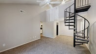 Located at 9205 Cedar Springs Pl in Louisville, KY, this two-story home offers a well-organized layout across two floors. The main level is anchored by a generous living area boasting soaring vaulted ceilings, a ceiling fan, and plush carpeting. A striking spiral staircase serves as both a functional and architectural focal point, leading to the upper level. Sliding glass doors in the living area fill the space with natural light and provide access to an outdoor area with views of surrounding greenery. The kitchen features white cabinetry, light countertops, a double stainless steel sink, and black appliances, all set on light wood-style flooring. The main level also includes an entrance, hallway, and a utility room for added convenience. The full bathroom is finished with a tiled floor, a combined tub and shower, a white vanity, and a large mirror with overhead lighting. The primary bedroom on the main floor is notably spacious, offering two closets and neutral carpet flooring. Upstairs, the loft-style second bedroom features a vaulted, sloped ceiling with a ceiling fan and a window that brings in natural light, creating a cozy and private retreat.