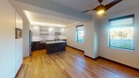 Located at 816 Porter Ave in Eau Claire, Wisconsin, this single-floor space showcases a contemporary design with carefully selected finishes throughout. The open-concept living and kitchen area is unified by warm hardwood flooring and crisp white walls, creating a bright and welcoming atmosphere. A ceiling fan overhead and a window overlooking greenery add comfort and natural light to the living space, which also features a wall-mounted dark wood cabinet that serves as a functional accent piece.

The kitchen is well-appointed with a large granite-topped island illuminated by pendant lighting, dark wood lower cabinetry, white upper cabinets, and open wood shelving. A full white subway tile backsplash, stainless steel farmhouse sink, stainless steel appliances—including a refrigerator, range, and dishwasher—and recessed lighting complete the modern culinary space.

A separate bedroom offers hardwood floors, a tall window with outdoor views, and a clean, minimalist design. The bathroom features bold deep-blue walls, large-format marble-look tile flooring, a glass-enclosed walk-in shower with marble tile surround, and a wood-toned vanity. A dedicated laundry room includes full-size washer and dryer units with built-in shelving above for added storage.