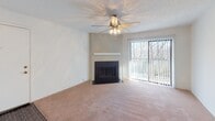 This single-floor residence offers a functional and straightforward layout with a variety of comfortable living spaces. The living room serves as the centerpiece of the home, featuring a classic fireplace with a clean mantle surround, plush wall-to-wall carpeting, and a ceiling fan with integrated lighting. A large sliding glass door floods the room with natural light and provides views of surrounding greenery, creating a bright and airy atmosphere.

The living area flows openly toward the kitchen, which features white cabinetry, a countertop peninsula, and dark flooring that contrasts the carpeted areas. This open sightline between the living and kitchen spaces supports easy movement and a connected feel throughout the common areas.

The bedrooms are carpeted in warm neutral tones and finished with crisp white walls. Each room is equipped with a window fitted with horizontal blinds, allowing adjustable natural light to filter in. Textured popcorn ceilings are consistent throughout the bedrooms. The rooms offer clean, versatile spaces well-suited for a variety of uses.

Overall, the residence presents a practical and well-organized floor plan with consistent finishes, including neutral carpeting, white walls, and standard fixtures throughout, making it a comfortable and move-in ready living space.
