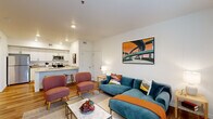 Located at 1932 NE 179th St in Ridgefield, WA, this thoughtfully designed one-bedroom, one-bathroom residence offers a comfortable and functional single-floor layout. The bright living room features wood-style flooring, large windows that invite natural light, a private entry door, and a wall-mounted mini-split HVAC unit for year-round climate control. The open-concept design connects the living area seamlessly to the kitchen, which is outfitted with white shaker cabinetry, light quartz countertops, a peninsula with bar seating, and a full suite of stainless steel appliances including a refrigerator, range, and microwave. The bedroom is a cozy retreat highlighted by a bold accent wall, carpeted flooring, a large window, and a dedicated walk-in closet. The clean, white bathroom includes a soaking tub with shower, wood-style flooring, and a stacked in-unit washer and dryer — a highly practical feature. A hallway connects the rooms efficiently, contributing to the unit's smart use of space. With contemporary finishes throughout and a cohesive modern aesthetic, this residence offers a polished and move-in-ready living experience in Ridgefield's growing community.