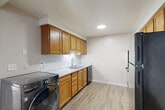 Located at 159 S Grove St in Ypsilanti, Michigan, this one-bedroom, one-bathroom unit offers a practical and well-organized single-floor layout. The living room is a bright, open space featuring plush carpeting, baseboard heating, a window with vertical blinds, and a wall-mounted air conditioning unit, allowing for comfortable year-round living. A ceiling fan with a built-in light fixture adds functionality to both the living area and the bedroom, which is a generously sized, carpeted retreat with its own baseboard heating and a window that brings in natural light.

The kitchen is equipped with warm oak cabinetry, light granite-style countertops, a stainless steel sink, a dishwasher, a black refrigerator, and a range. Light luxury vinyl plank flooring runs through the kitchen and flows into the dining area. Notably, the kitchen also accommodates an in-unit front-load washer, adding everyday convenience. Two closets provide ample storage throughout the unit.

The bathroom features wood-look LVP flooring, a white tiled tub-shower combination, a toilet, and a vanity with sink. Two hallways connect the rooms, contributing to a smooth and logical flow throughout the space.